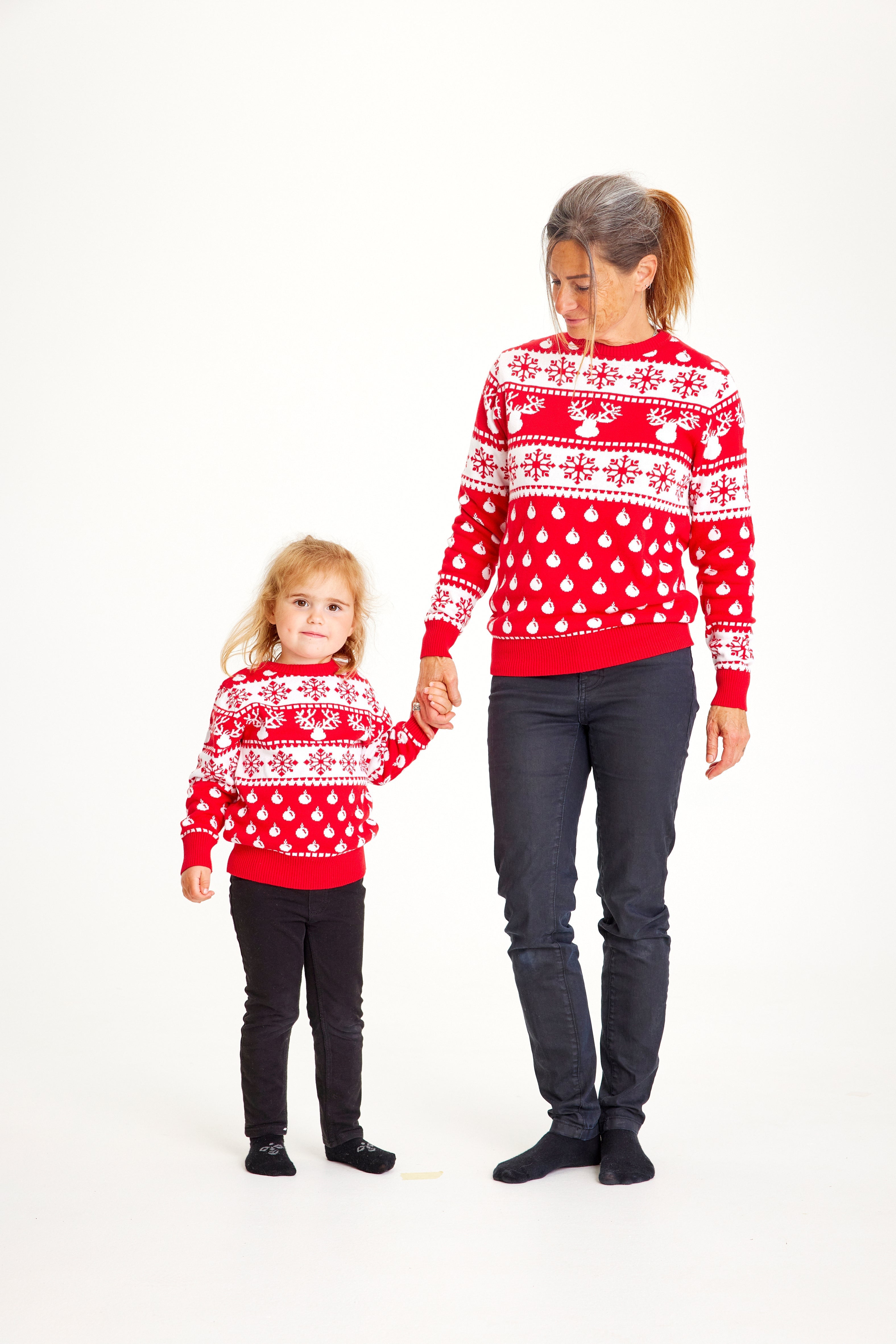 Et barn og en kvinne iført en rød julegenser med julemønster og reinsdyr.